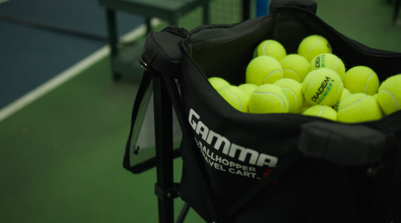 A ball cart loaded with tennis balls courtside at Match Point KC
